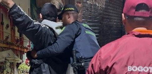 Policía requisando a un hombre en compañía de un gestor del orden
