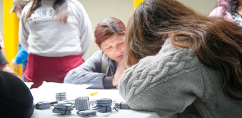 Dos mujeres sentadas en una mesa y otra mujer de pie