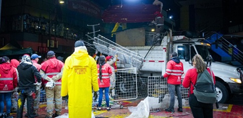 Varios hombres y mujeres subiendo una reja a un camión recolector