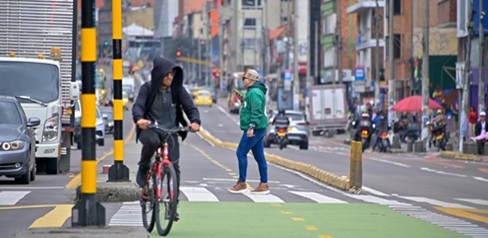 Hombre montando bicicleta y otro más caminando