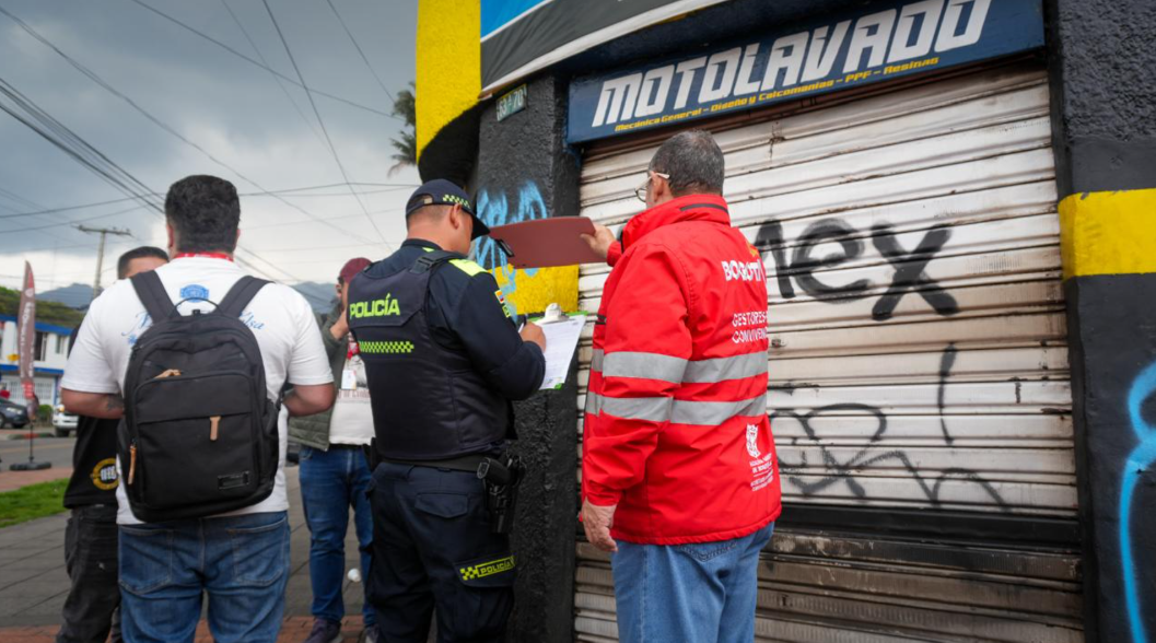 Policía y funcionario de la alcaldía sellando establecimiento comercial