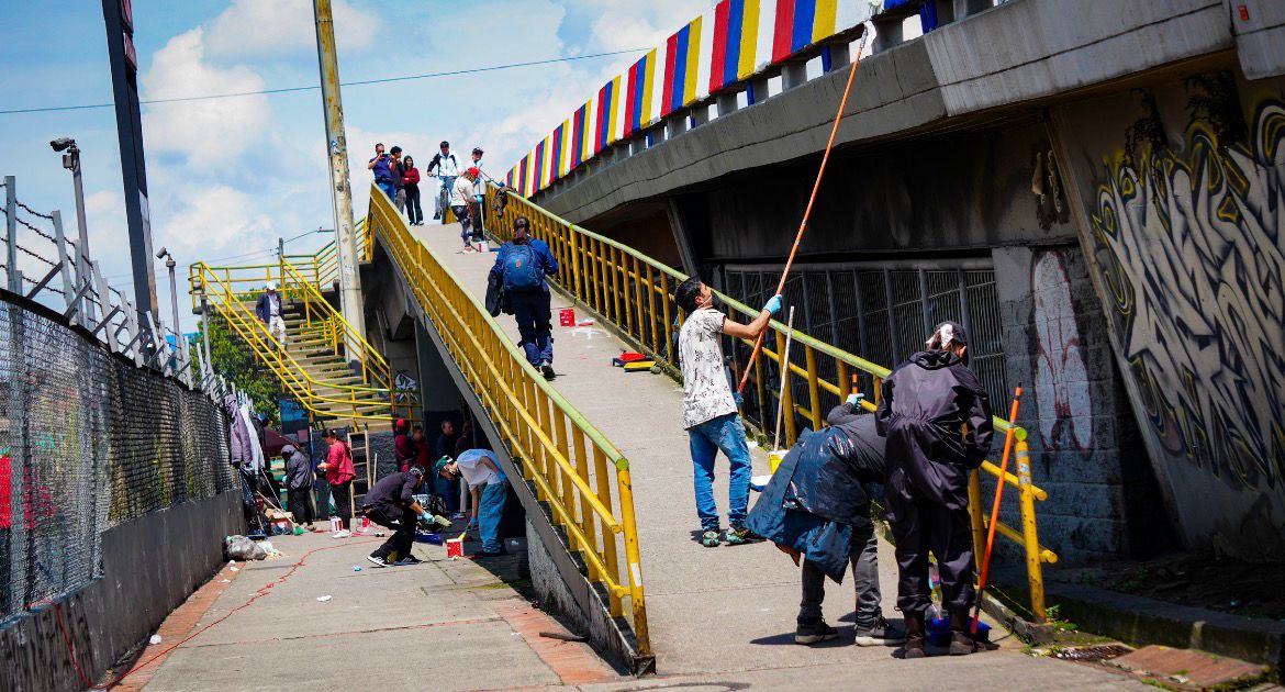 Varias personas pintando un puente y otra pasando sobre el