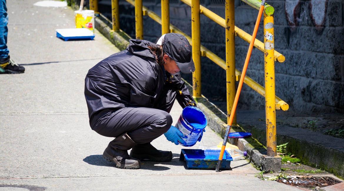 Una mujer con un  bote de pintura azul