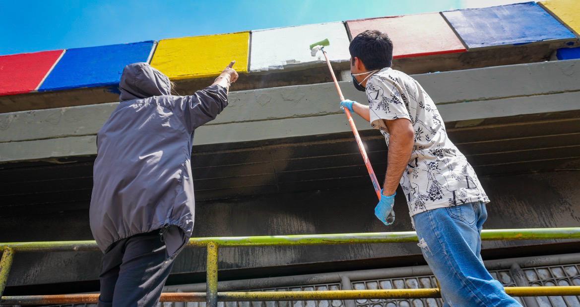 Un hombre pintando un puente y otra persona señalándolo