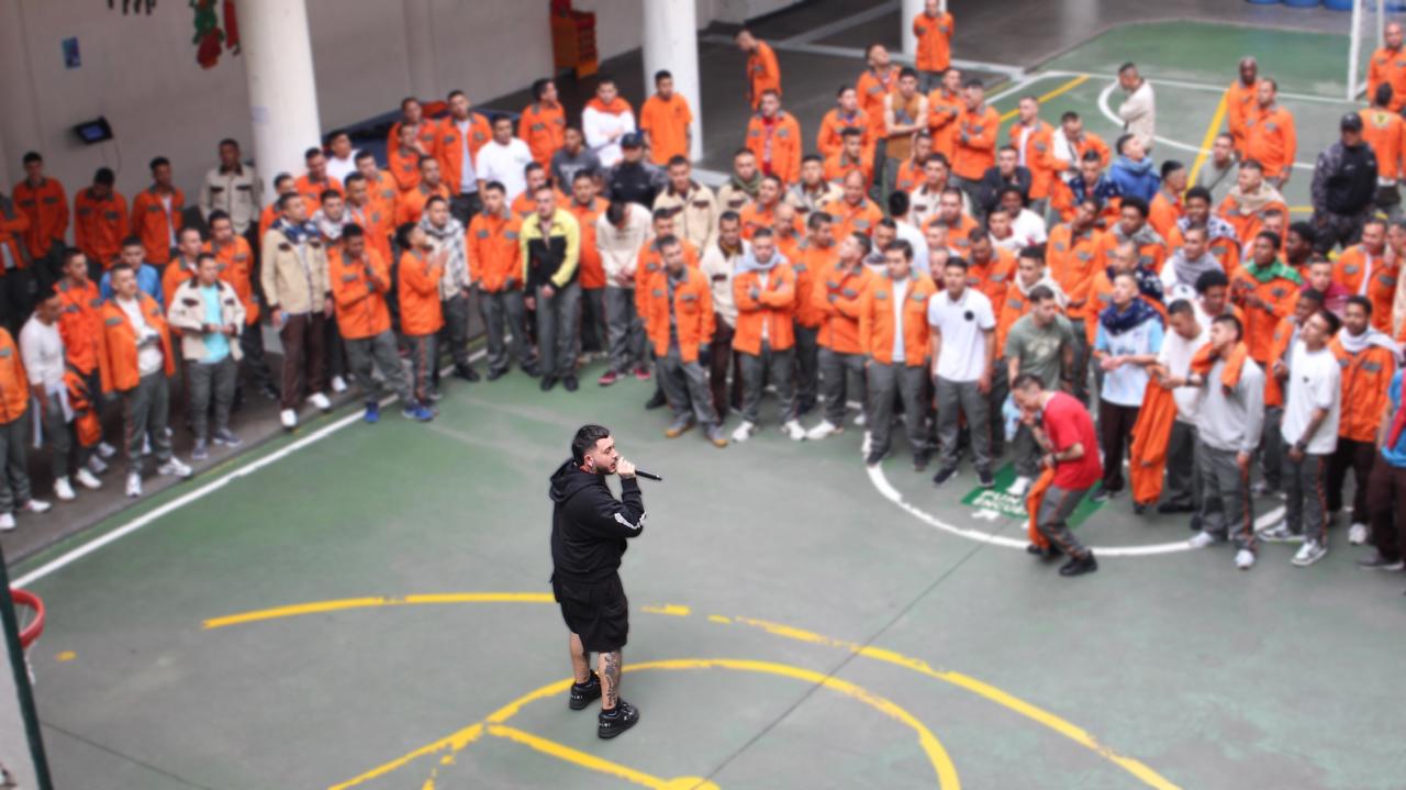 Hombre cantando con micrófono frente a varios hombres