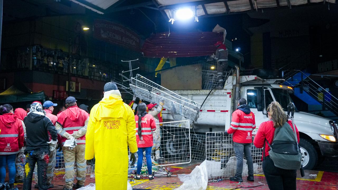 Varios hombres y mujeres subiendo una reja a un camión recolector
