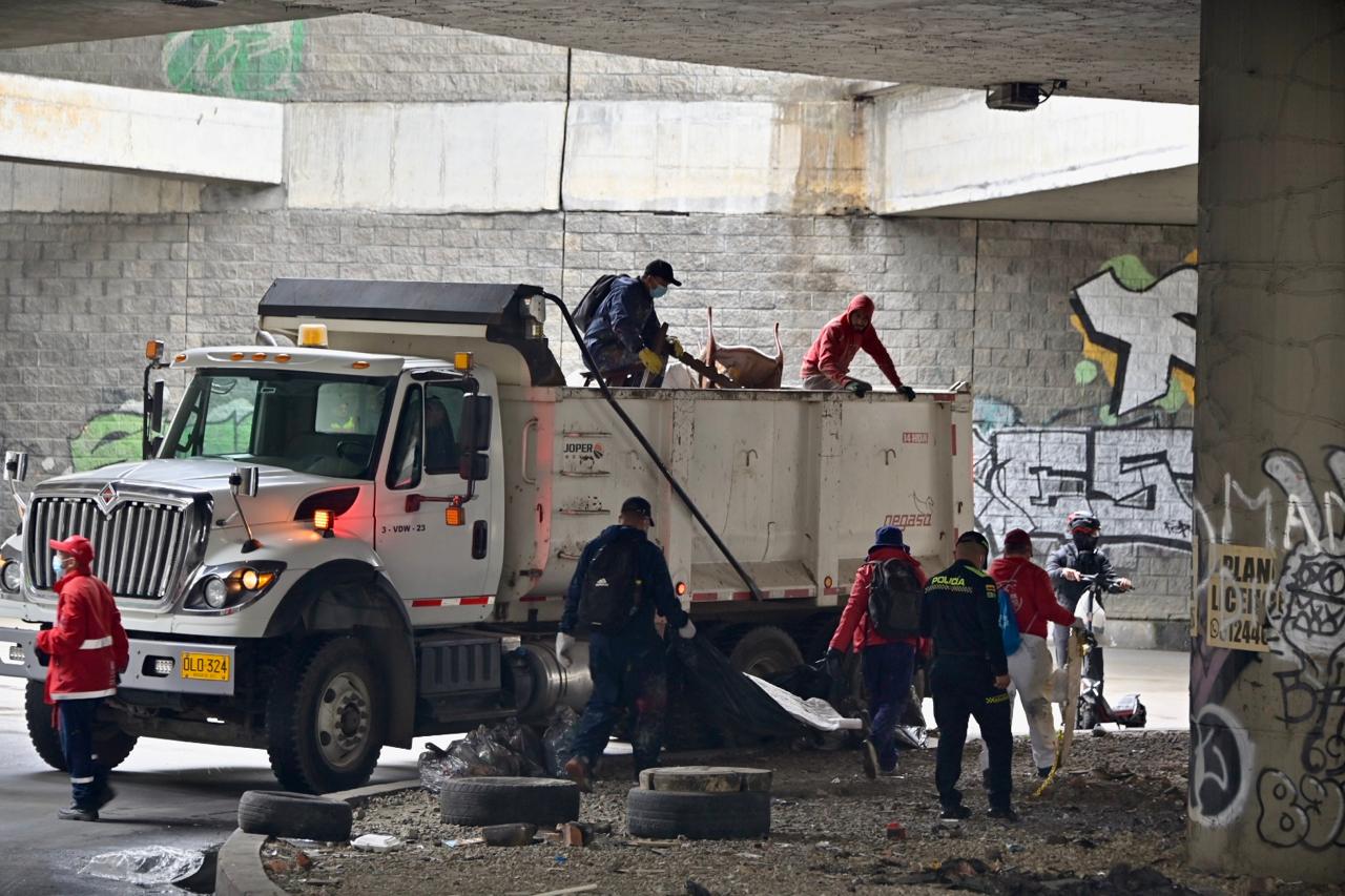 Intervención al espacio público en Tercer Milenio y puente de Bicentenario dejó varios cambuches desmontados y seis toneladas de residuos retiradas Varias personas subiendo basura a un camión recolector