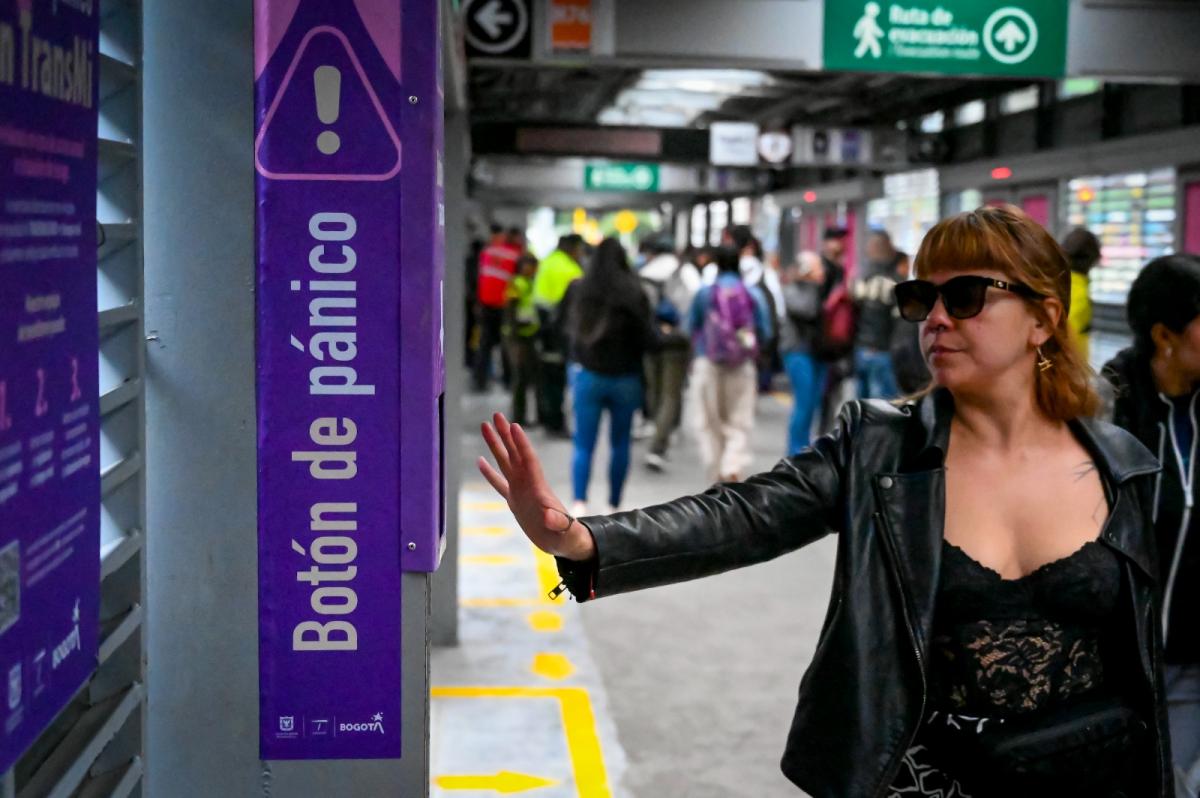 Mujer tocando el botón de pánico en estación de Transmilenio. Mujer tocando el botón de pánico en estación de Transmilenio.