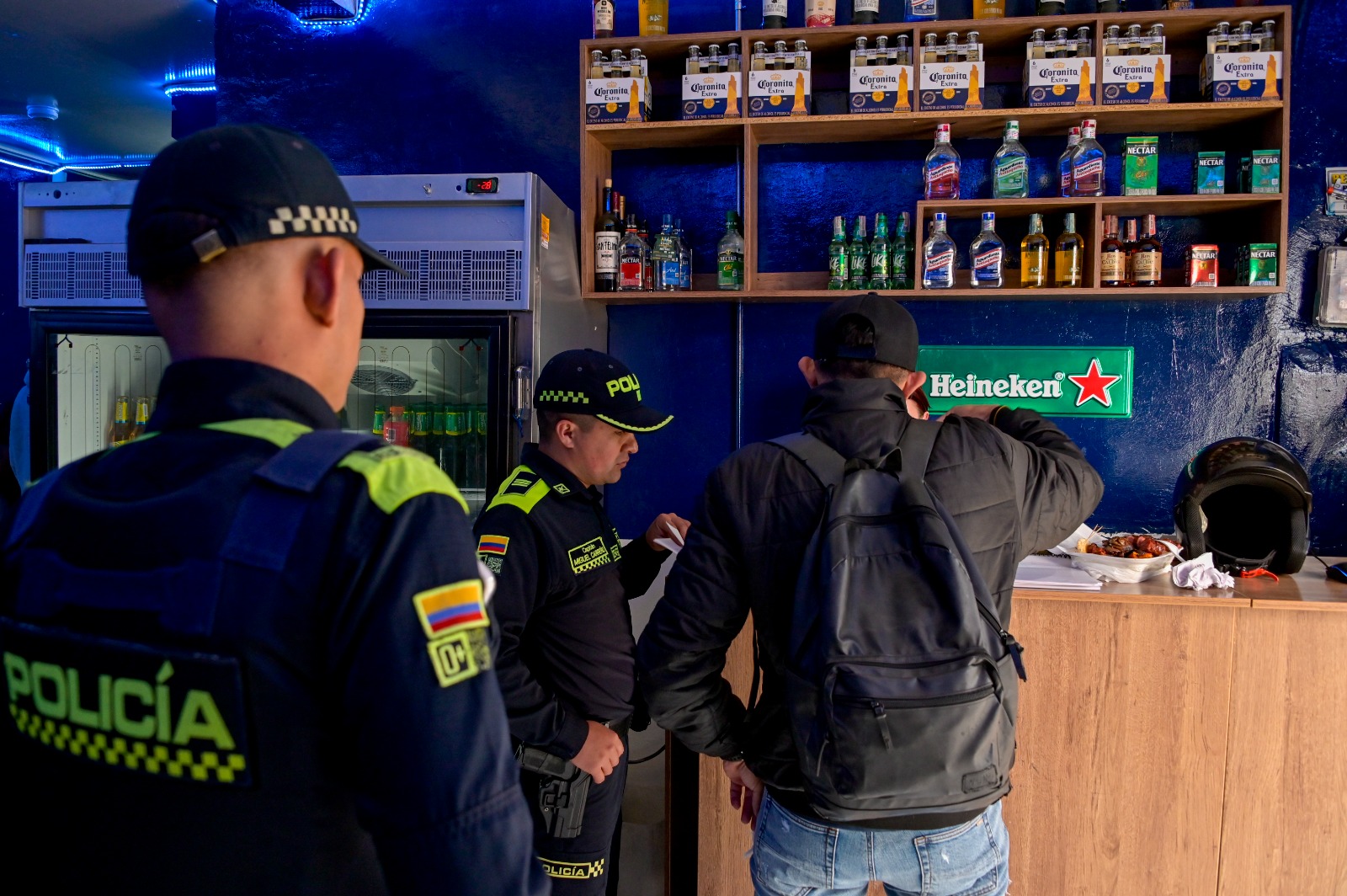 Dos Policías junto a un hombre en un establecimiento comercial