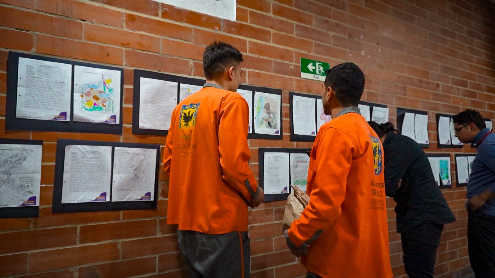 Dos hombres mirando dibujos pegados a una pared
