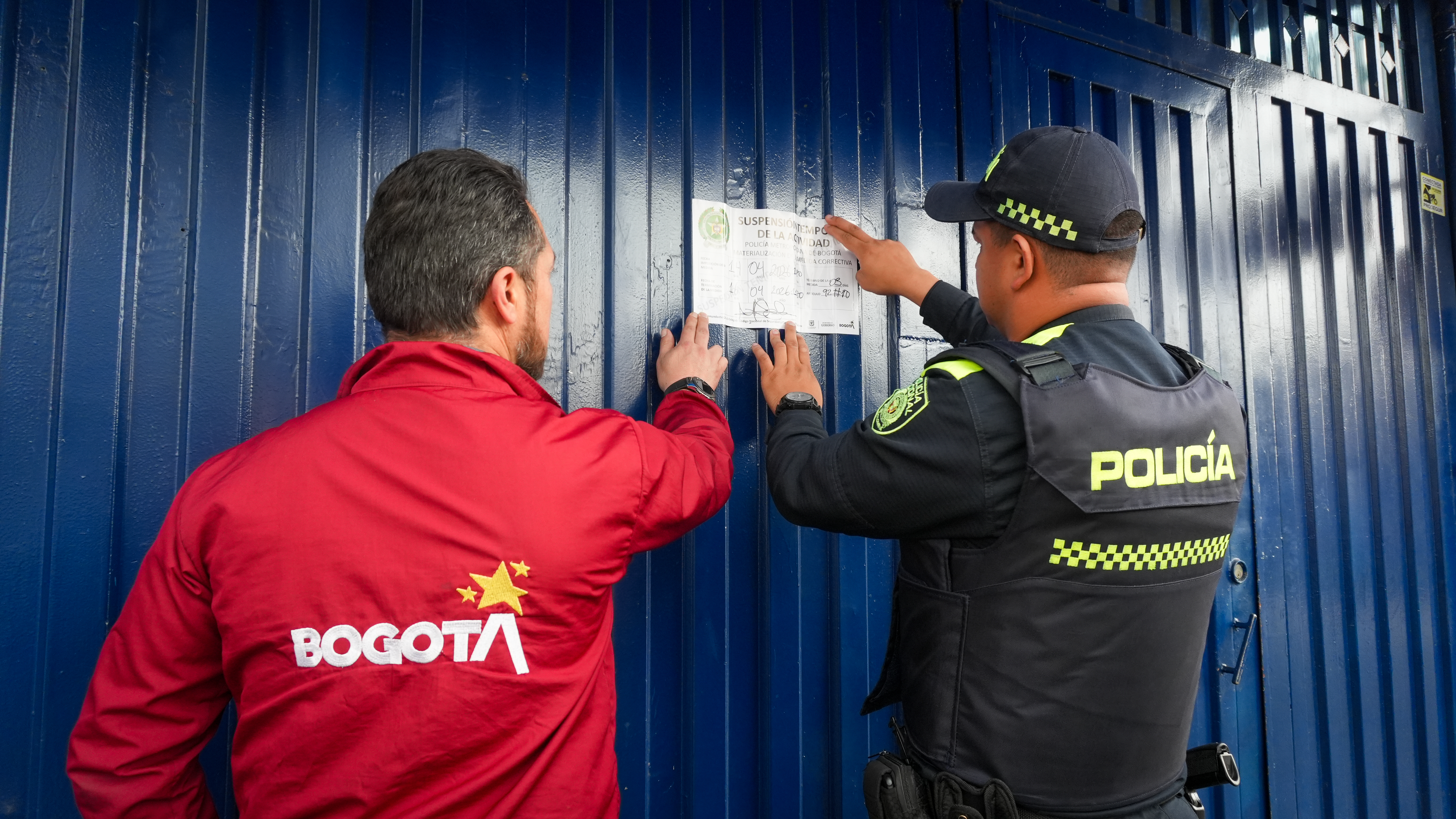 Policía y funcionario de la alcaldía sellando establecimiento comercial